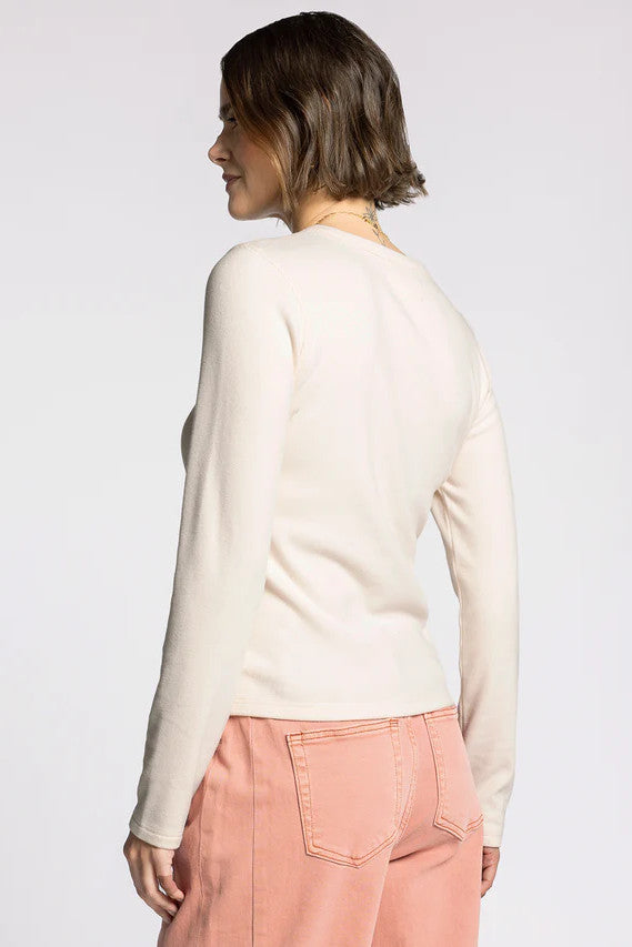 Woman wearing a white long-sleeve top and pink pants on a white background 