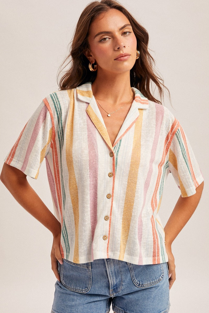 Woman wearing a colorful striped shirt with a neutral background