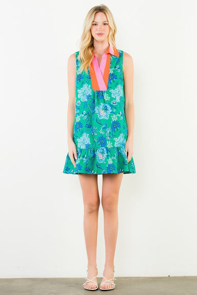 Woman wearing a greaan and blue floral dress with a pink and orange collar on a white background