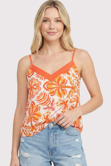 Woman wearing an orange floral tank top and blue jeans on a white background
