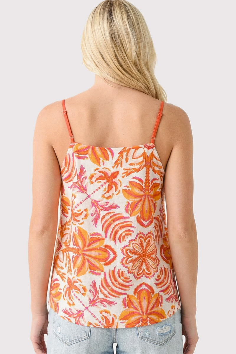Woman wearing a floral tank top with orange and pink flowers on a plain background