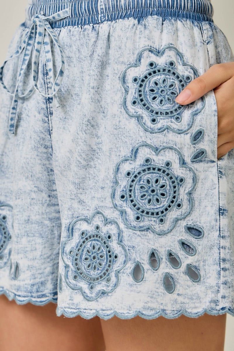 Denim shorts with decorative embroidery on a person's waist.