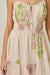 Beige dress with pink and green floral patterns on a plain background