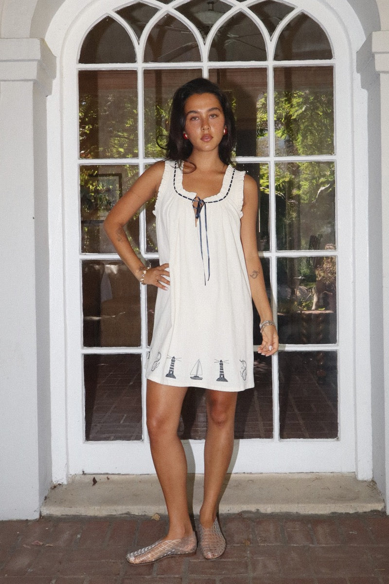 Woman in a white dress standing in front of a glass door.