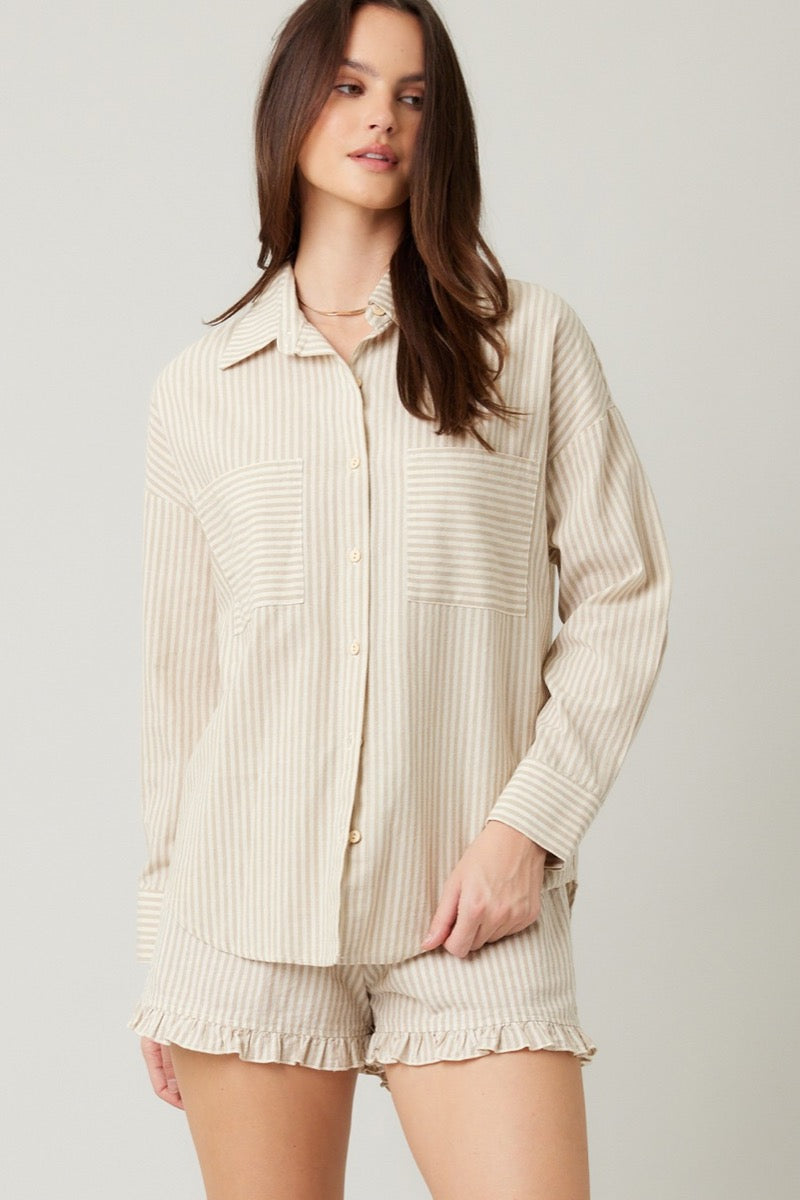 Woman wearing a beige striped shirt and shorts set on a plain background