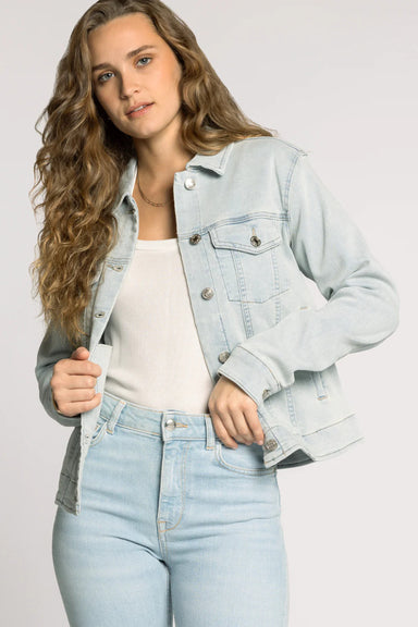 Woman wearing a light blue denim jacket and jeans on a plain background