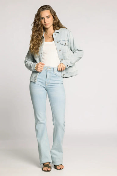 Woman wearing a light blue denim jacket and jeans on a plain background